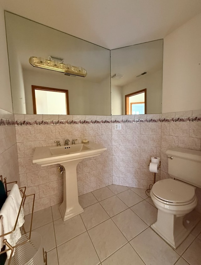 half bathroom featuring tile walls, toilet, tile patterned flooring, and visible vents