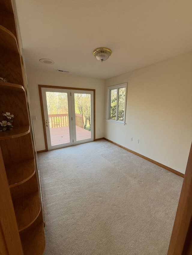 empty room featuring carpet, visible vents, and baseboards