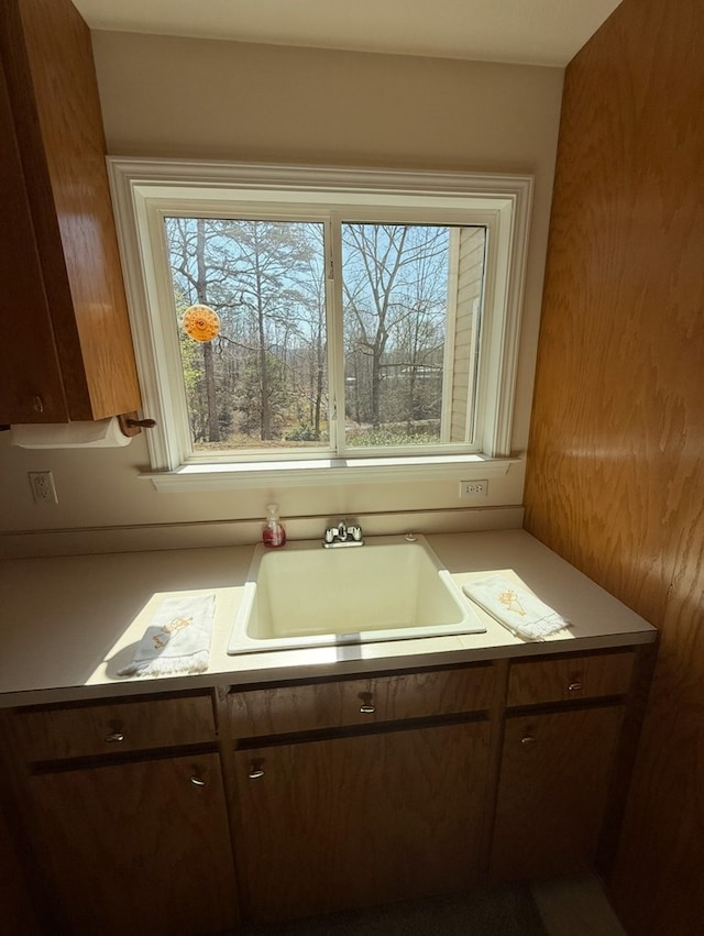 kitchen featuring dark brown cabinetry, light countertops, a sink, and a healthy amount of sunlight