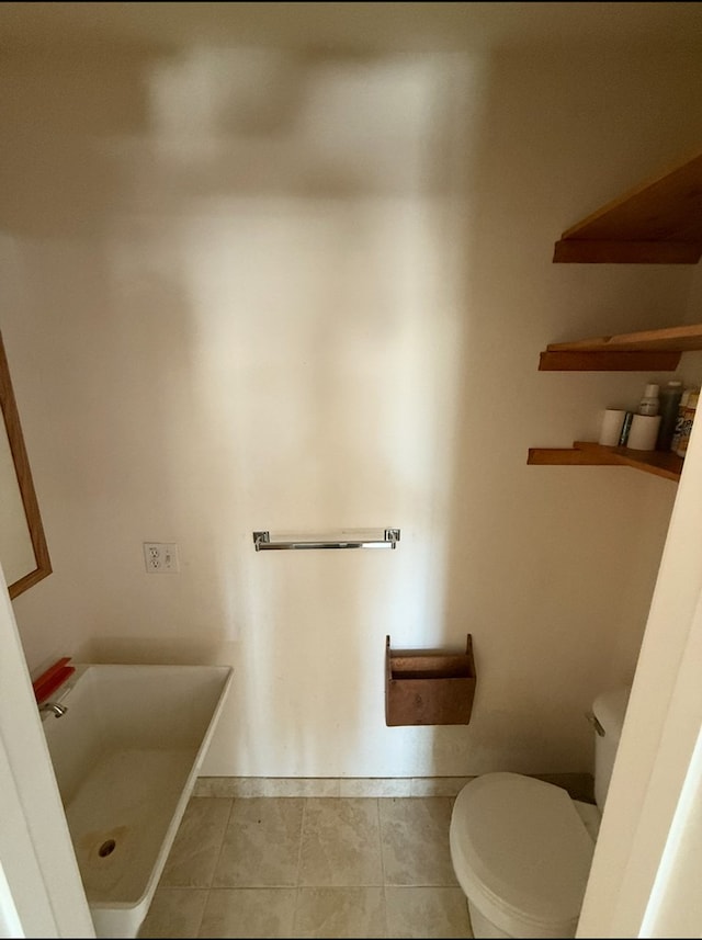 bathroom featuring a bathtub, tile patterned flooring, baseboards, and toilet