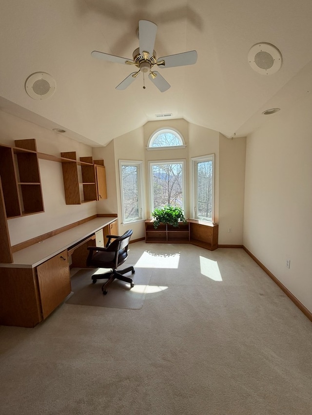 home office with visible vents, baseboards, ceiling fan, vaulted ceiling, and light carpet