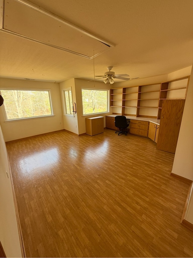unfurnished living room with baseboards, a ceiling fan, attic access, and wood finished floors