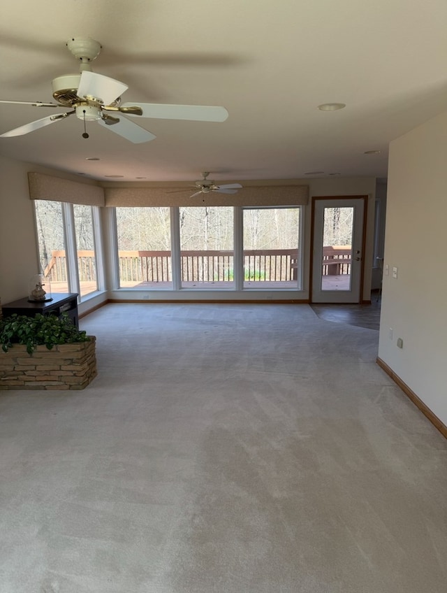 unfurnished living room with baseboards, a ceiling fan, and carpet