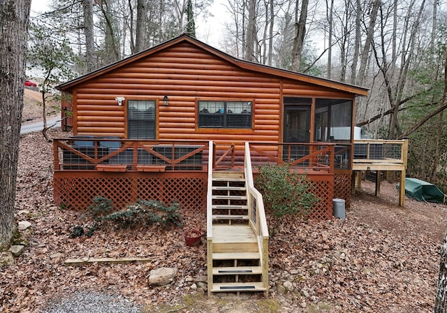 rear view of property featuring a sunroom and a wooden deck