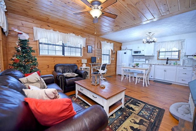 living room featuring light wood-type flooring, a wealth of natural light, wood walls, and sink