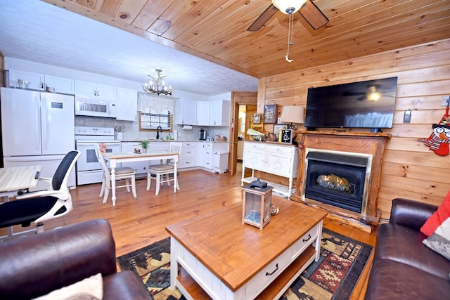 living room with wood walls, light hardwood / wood-style floors, wood ceiling, and sink