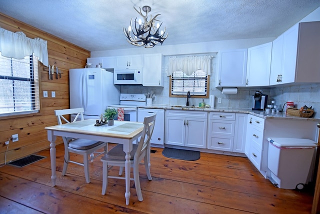 kitchen with white appliances, sink, wood-type flooring, white cabinets, and hanging light fixtures