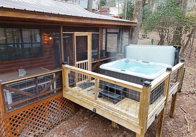 wooden deck with a sunroom and a hot tub