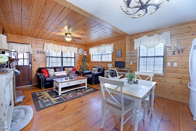 dining space with ceiling fan, wood-type flooring, wooden walls, and wooden ceiling