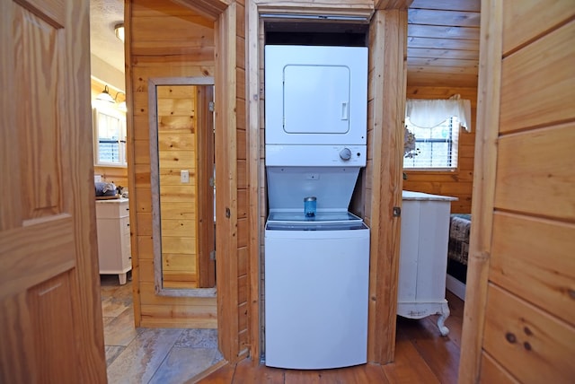 laundry room with stacked washer and clothes dryer and wood walls