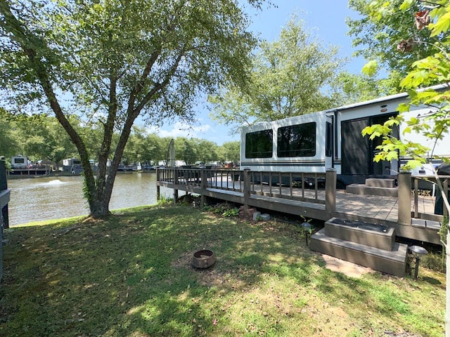 dock area featuring a deck with water view and a lawn