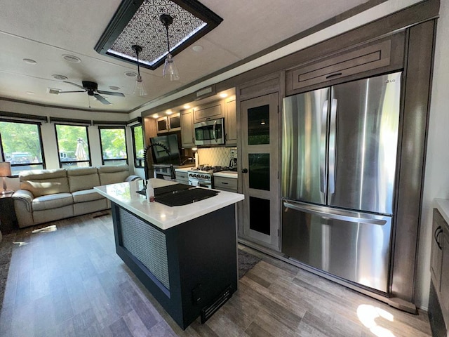 kitchen featuring sink, ornamental molding, ceiling fan, an island with sink, and appliances with stainless steel finishes