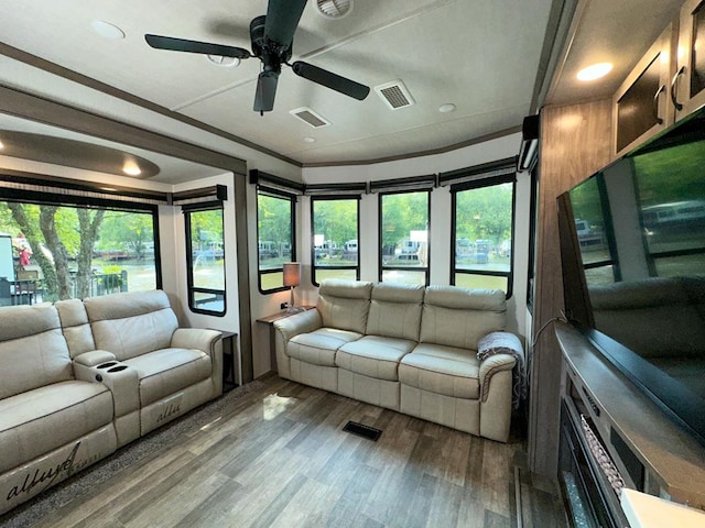 unfurnished living room with wood-type flooring, ceiling fan, and a wealth of natural light