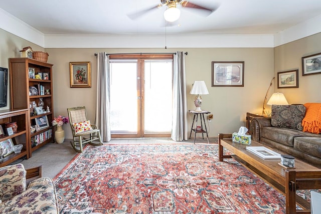 living room featuring ceiling fan, crown molding, and carpet floors