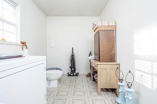 bathroom with a textured ceiling, washer / clothes dryer, and toilet