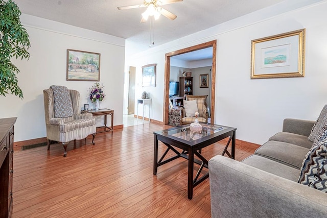 living room featuring ceiling fan, a textured ceiling, and light wood-type flooring