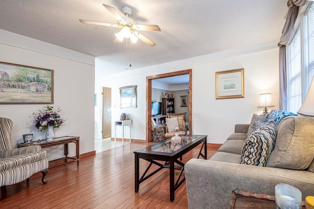 living room with ceiling fan, wood-type flooring, and a textured ceiling