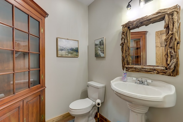 half bath featuring baseboards and toilet