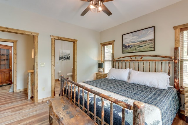 bedroom with ensuite bathroom, ceiling fan, light wood-style flooring, and baseboards