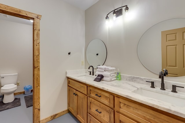 full bath with toilet, double vanity, baseboards, and a sink