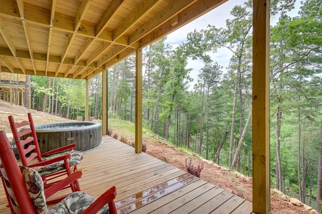 deck featuring a hot tub and a forest view