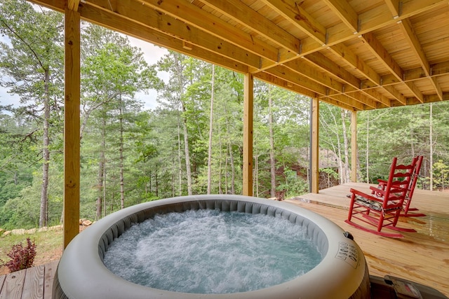 view of patio featuring a forest view, an outdoor hot tub, and a wooden deck