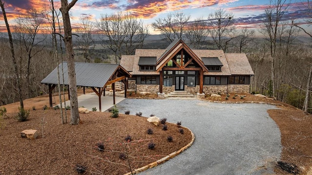 rustic home featuring stone siding and gravel driveway