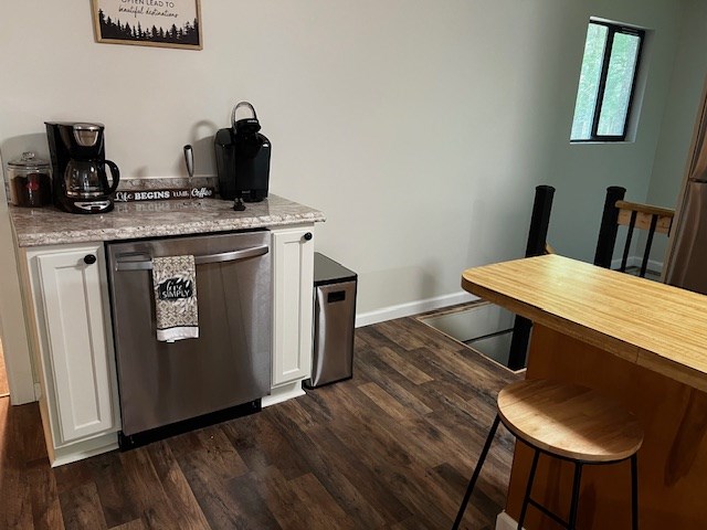 kitchen featuring dishwasher, light stone countertops, dark hardwood / wood-style floors, and white cabinets