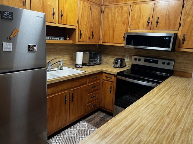 kitchen featuring appliances with stainless steel finishes, sink, and dark hardwood / wood-style flooring