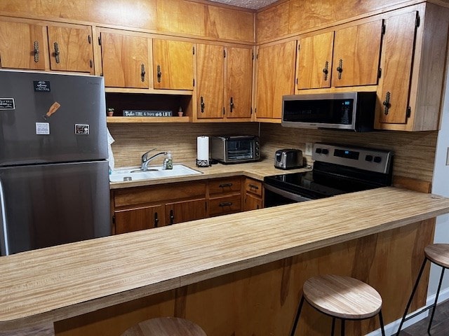 kitchen with appliances with stainless steel finishes, a breakfast bar, and sink