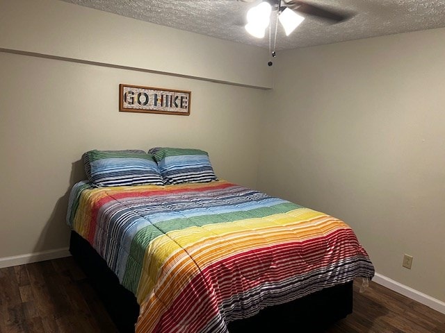 bedroom with dark hardwood / wood-style flooring, ceiling fan, and a textured ceiling