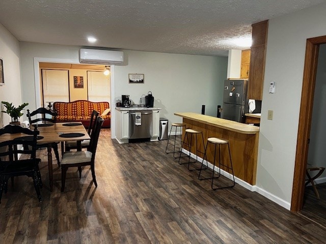 dining area featuring bar, dark hardwood / wood-style floors, an AC wall unit, and a textured ceiling