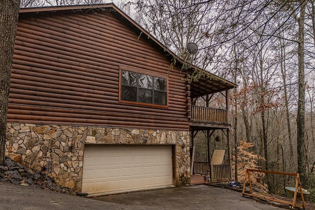 view of side of home featuring a garage and a balcony