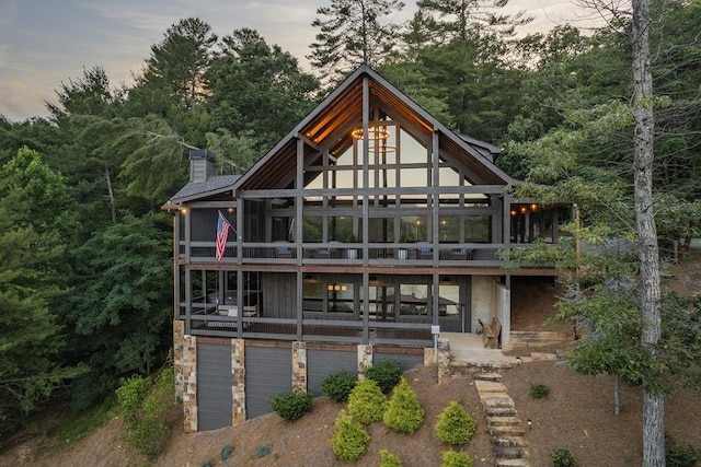 back house at dusk featuring a sunroom