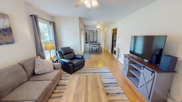 living room featuring heating unit, ceiling fan, and light hardwood / wood-style floors