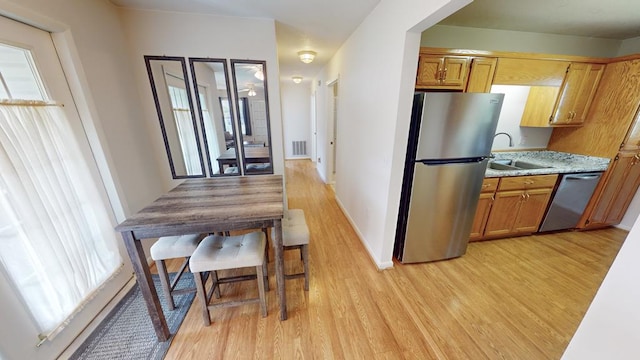 kitchen featuring appliances with stainless steel finishes, a wealth of natural light, sink, and light hardwood / wood-style flooring