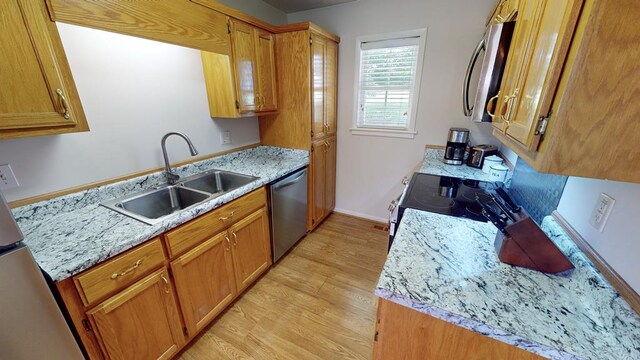 kitchen featuring light hardwood / wood-style flooring, light stone counters, stainless steel appliances, and sink