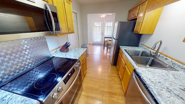 kitchen with french doors, tasteful backsplash, light hardwood / wood-style floors, stainless steel appliances, and sink