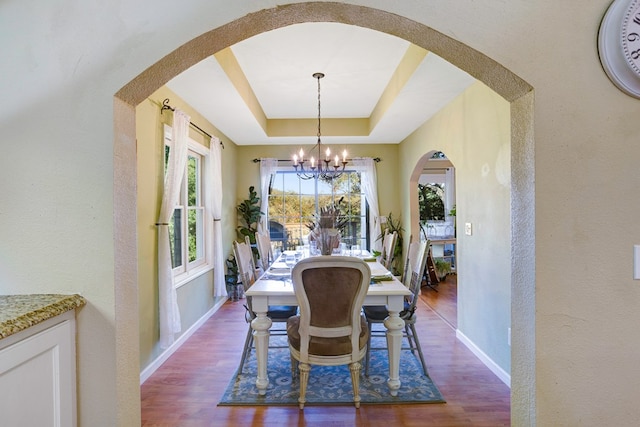 dining space with a notable chandelier, dark hardwood / wood-style floors, and a raised ceiling