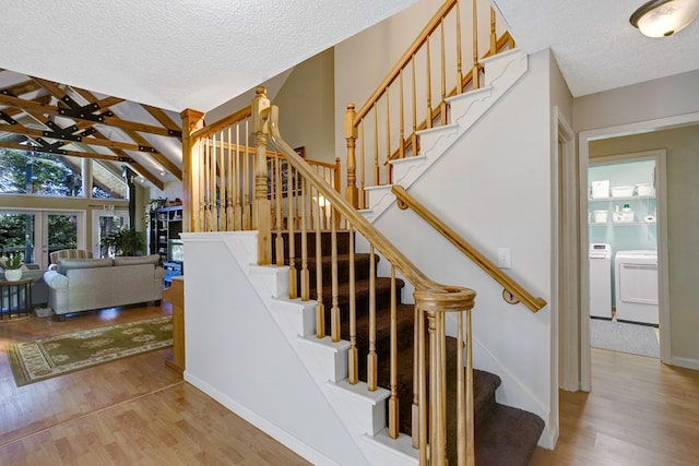 stairs featuring washer and dryer, hardwood / wood-style floors, vaulted ceiling with beams, and a textured ceiling