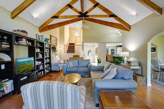 living room with beamed ceiling, ceiling fan, wood-type flooring, and high vaulted ceiling