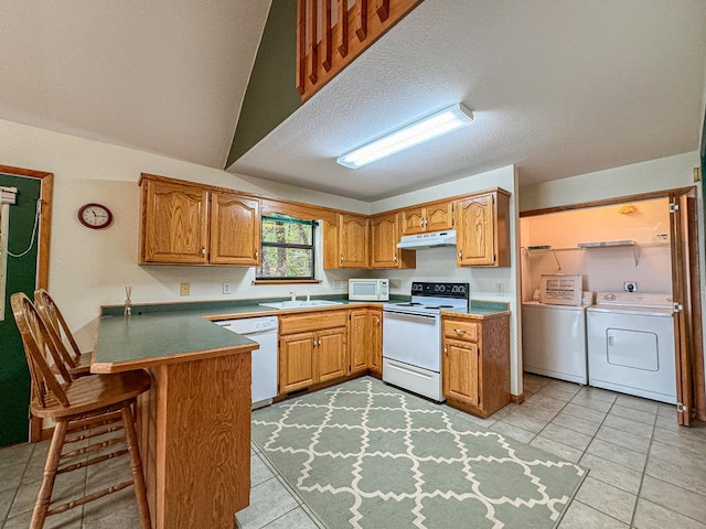 kitchen with independent washer and dryer, white appliances, sink, vaulted ceiling, and light tile patterned flooring