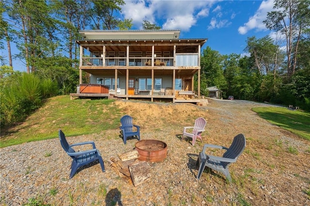 rear view of property featuring a lawn, a deck, and an outdoor fire pit