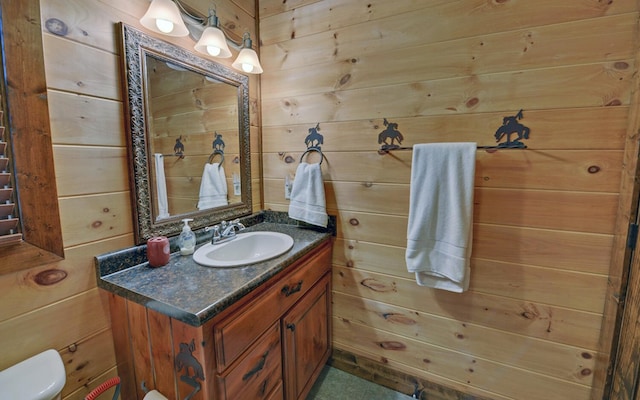 bathroom featuring wood walls, toilet, and vanity