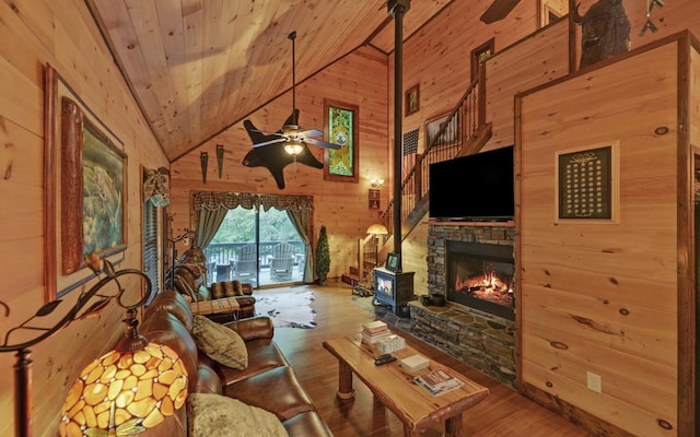 living area featuring wood walls, wood finished floors, ceiling fan, wooden ceiling, and high vaulted ceiling