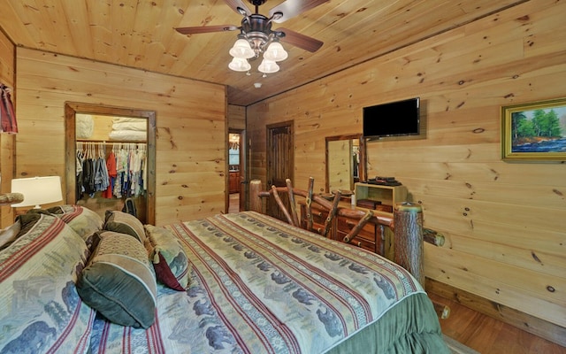 bedroom featuring wood walls, wood ceiling, a spacious closet, a closet, and wood finished floors