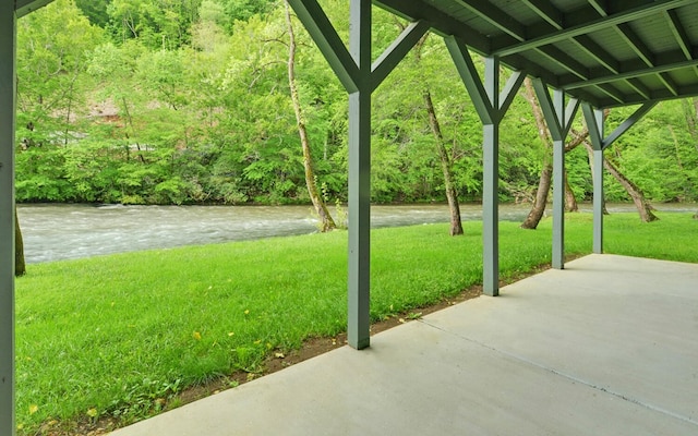 view of green lawn featuring a patio and a wooded view