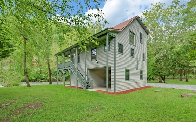 view of side of property with a lawn, stairway, and driveway