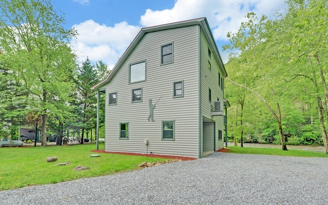 view of home's exterior with gravel driveway and a lawn