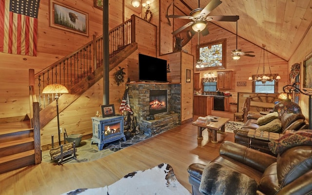 living room featuring high vaulted ceiling, wooden ceiling, wood walls, wood finished floors, and a ceiling fan